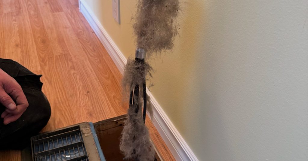 Air whip pulling dust and debris out of a floor vent in a Sudbury home