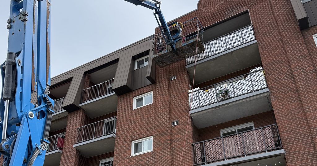 Boom lift reaching upper floor ductwork at a Sudbury apartment building