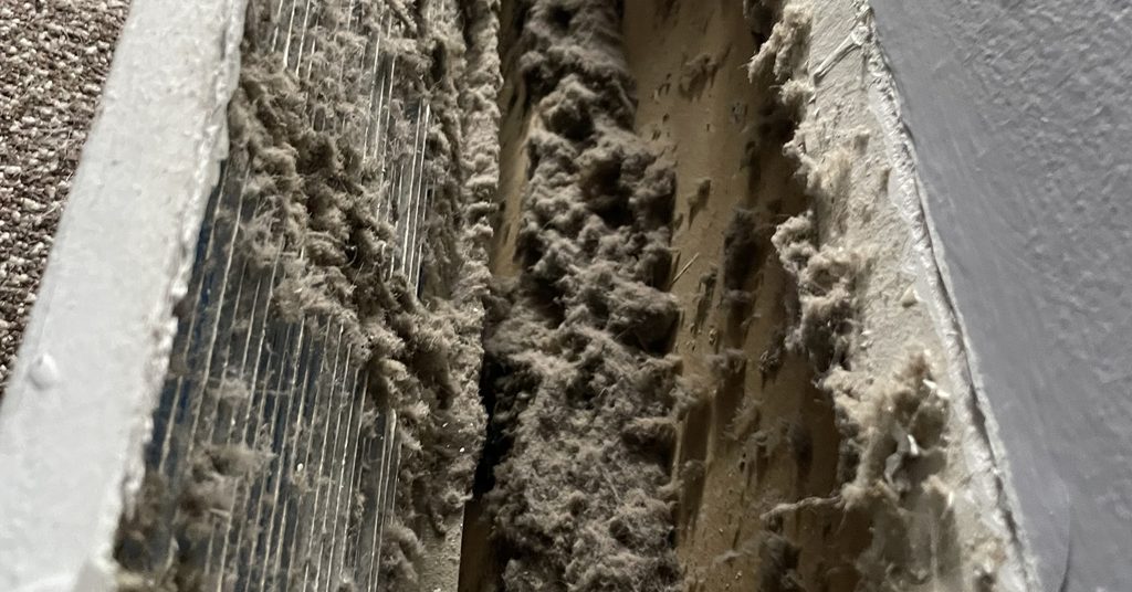 Duct opening packed with dust showing why regular air duct cleaning matters